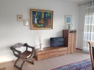 - un salon avec une télévision et une chaise dans l'établissement Nicoles Niedschlösschen, à Rehlingen-Siersburg