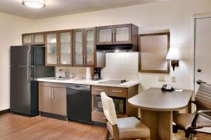 a kitchen with a black refrigerator and a table at Candlewood Suites Plano East, an IHG Hotel in Plano