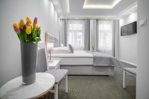 een slaapkamer met een bed en een vaas met bloemen op een tafel bij Kamienica Pod Neptunem in Puck