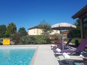 a swimming pool with lounge chairs and an umbrella at Auberge Bressane de Buellas in Buellas