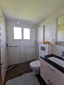 La salle de bains blanche est pourvue de toilettes et d'un lavabo. dans l'établissement BellaVista, à Emmetten