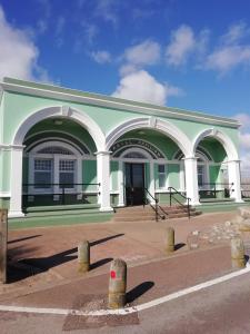 a green and white building with arches on a street at Ground Floor Apartment in Montrose