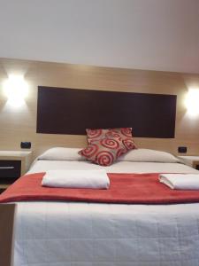 a large bed with red and white pillows on it at Hotel Playa in Viareggio