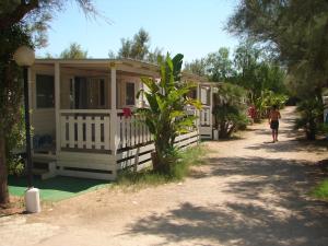a person walking past a house with a person walking towards it at Camping Torre Castiglione in Torre Lapillo