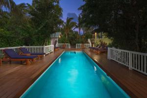 - une piscine sur une terrasse avec des chaises et des arbres dans l'établissement Weezie's Ocean Front Hotel and Garden Cottages, à Caye Caulker