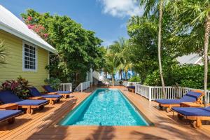 a swimming pool with chairs and a house at Weezie's Ocean Front Hotel and Garden Cottages in Caye Caulker