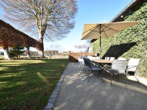 - une table et des chaises avec un parasol dans la cour dans l'établissement Quaint Cottage in Kuchelscheid with Terrace, à Küchelscheid