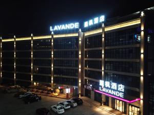 - un grand bâtiment avec des panneaux de néon la nuit dans l'établissement Lavande Hotel Huizhou High-speed Railway South Station Wanlian Square, à Huizhou