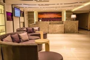 a lobby with couches and a table and a television at Lavande Hotel Huizhou Nan Station Wanda Square in Huiyangshi