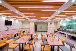a dining room with tables and chairs and a tv at Lavande Hotel Qingyuan Sports Park Municipal Government in Qingyuan