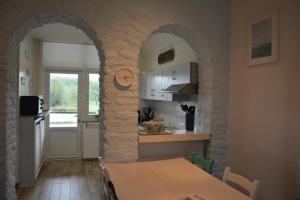 een keuken met een tafel en een stenen muur bij Vakantiehuis 't Geultje in Schin op Geul