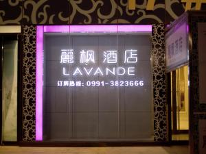 un cartel en la ventana de una tienda con una luz púrpura en Lavande Hotel Urumqi High-speed Railway wanda plaza en Ürümqi