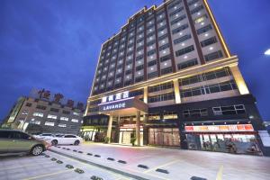 a tall building with cars parked in a parking lot at Lavande Hotel Zhongshan Shaxi in Changzhou