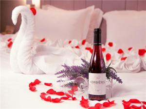 a bottle of wine sitting on a bed with red roses at Lavande Hotel Heyuan Zijin in Heyuan