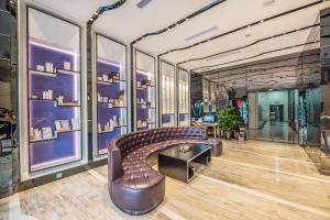 Cette chambre comprend un canapé et un mur de fenêtres. dans l'établissement Lavande Hotel Chongqing Tongliang Wanda Plaza Gas Tower, à Tongliang