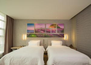 two beds in a hotel room with a painting on the wall at Lavande Hotel Dongguan Humen Wanda Square in Dongguan