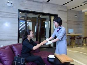 Una donna sta aiutando un'altra donna in una stanza di Lavande Hotel Zhanjiang Xuwen Tianrunhui a Xuwen