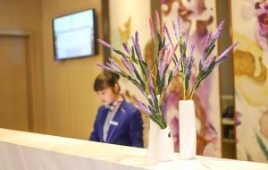 a table with a vase with purple flowers on it at Lavande Hotel Puning International Commodity Mall in Jieyang