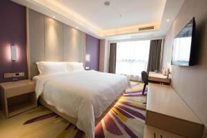 a hotel room with a bed and a flat screen tv at Lavande Hotel Luzhou BBQ new World in Luzhou