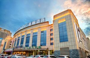 um grande edifício com carros estacionados num parque de estacionamento em Lavande Hotel Changji Changning Road em Changji