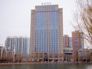 un edificio alto en una ciudad junto a un cuerpo de agua en Lavande Hotel Korla city government swan lake, en Korla