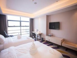 um quarto de hotel com duas camas e uma televisão de ecrã plano em Lavande Hotel Korla city government swan lake em Korla