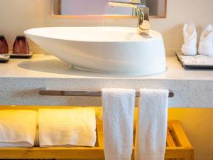 a bathroom counter with a white sink and towels at Lavande Hotel Mianyang Santai North Passenger Transport Center Binjiang Park in Mianyang +28 photos