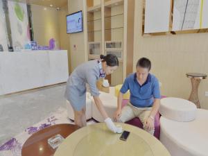 une femme et un homme travaillant sur des toilettes dans une pièce dans l'établissement Lavande Hotel Xingyi Jushan Avenue, à Xiawutun
