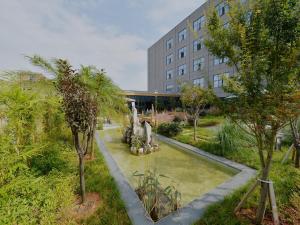 un jardin avec une fontaine en face d'un bâtiment dans l'établissement Lavande Hotel Xingyi Jushan Avenue, à Xiawutun