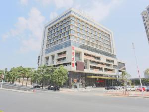 東莞市にあるLavande Hotel Dongguan Liaobu Centerの前に駐車場がある高層ビル