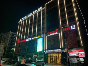 a large building with neon signs in a city at night at Lavande Hotel Huizhou Xinxu Government Square in Niu'ao