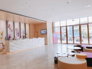 a lobby with tables and chairs in a building at Lavande Hotel Huizhou Xinxu Government Square in Niu'ao