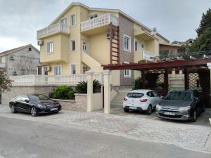 zwei Autos auf einem Parkplatz vor einem Haus geparkt in der Unterkunft Apartments Sandra in Tivat