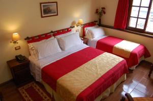 a bedroom with two beds with red and white sheets at Hosteria Sirenuse in Mar del Plata