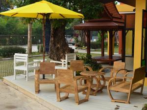 un groupe de chaises et de tables et un parapluie jaune dans l'établissement Boonme Heritage, à Phitsanulok