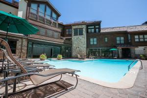 una gran piscina con sillas y sombrilla en Northwood's Ski-In Ski-Out by Vail Realty, en Vail