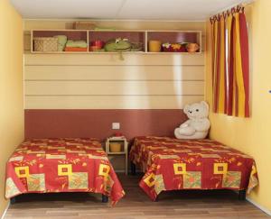 un dormitorio infantil con 2 camas y un osito de peluche en Résidence Santa, en Ghisonaccia