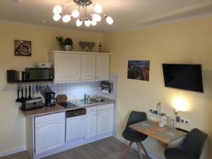 a kitchen with white cabinets and a sink and a table at Haus Solymar App. 59 in Grömitz