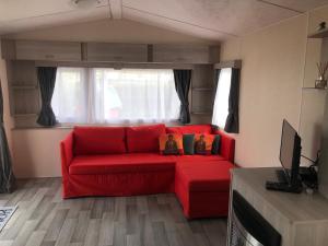 a red couch sitting in a living room at Luxe Chalet op camping Duindoorn, IJmuiden aan Zee, in de buurt van F1 circuit Zandvoort en Bloemendaal op loopafstand strand in IJmuiden