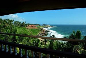 a view of the ocean from a balcony at Vijaya Varma Beach Resort in Kovalam