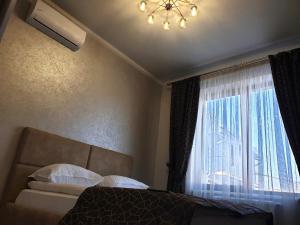 Un dormitorio con una cama y una ventana con una lámpara de araña. en Apartment Sweethome 1 FREE PARKING en Úzhgorod
