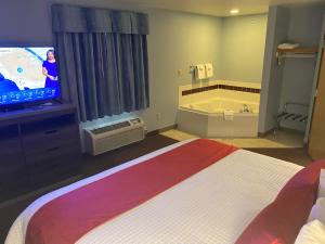 Habitación de hotel con cama, TV y bañera. en Garnett Hotel & RV Park en Garnett