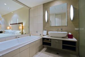 a bathroom with a tub and a sink and a mirror at The Rees Hotel & Luxury Apartments in Queenstown
