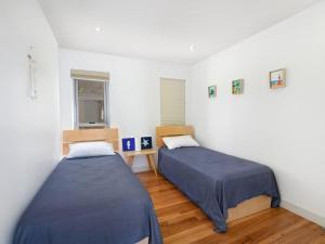two beds in a room with white walls and wooden floors at Rangoon Sunrise at Minnamurra in Minnamurra