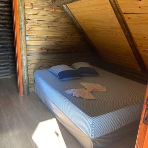 a bed in a wooden cabin with two pillows at CHALÉ ESTÂNCIA OURO VERDE in Lages +190 photos