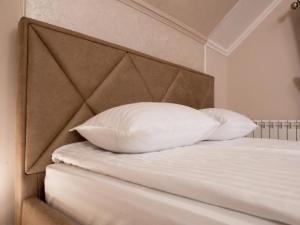 1 cama con 2 almohadas blancas y cabecero marrón en Apartment Sweethome 4 FREE PARKING, en Uzhhorod