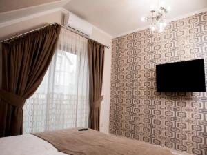 1 dormitorio con 1 cama y TV en la pared en Apartment Sweethome 4 FREE PARKING, en Uzhhorod