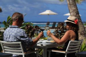 um homem e uma mulher sentados numa mesa com copos de vinho em Moana Sands Lagoon Resort - Adults Only em Rarotonga