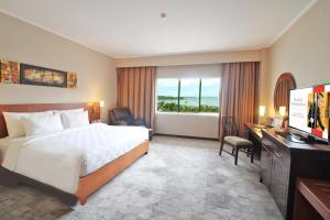 um quarto de hotel com uma cama, uma secretária e uma televisão em Swiss-Belhotel Manokwari em Manokwari