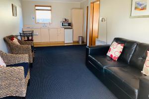 sala de estar con sofá de cuero negro y cocina en Admiral Court Motel & Apartments, en Invercargill